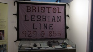 Fabric banner with letters 'Bristol Lesbian Line' and a phone number. 