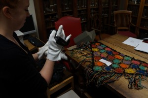 Conni films the shawl and piece of the fence, which are placed on the table in Special Collections at Bristol University